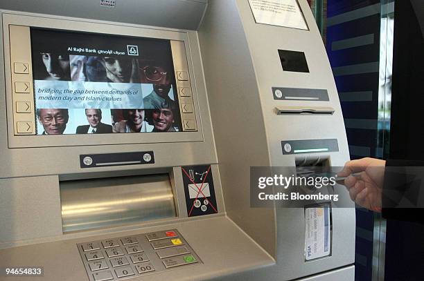 Customer relations officer demonstrates how to use an ATM at the Al Rajhi Bank in Kuala Lumpur, Malaysia, on Monday, Feb. 5, 2007.