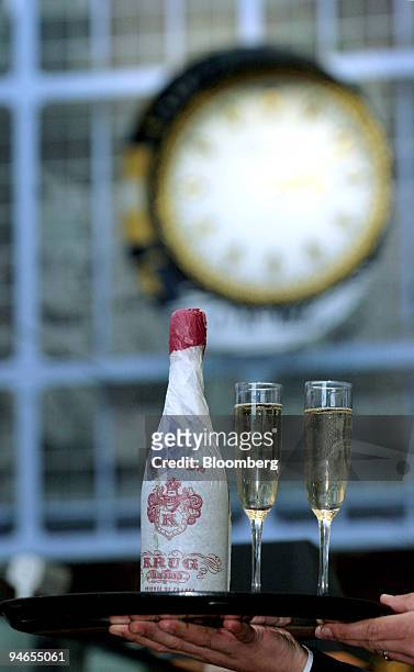 Waiter carries a tray with glasses of champagne and a bottle of Krug at the Champagne Bar at St. Pancras International Station in London, U.K., on...