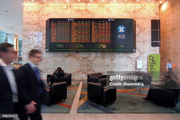 Workers walk past the Australian Securities Exchange stocks board in the lobby of Rialto Towers in Melbourne, Australia, on Monday, Dec. 3, 2007....