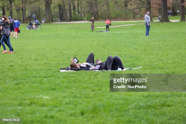 Two women lie on the grass on a cloudy spring day in Munich.