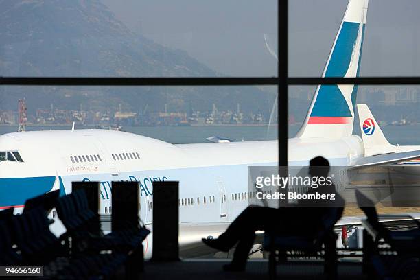 Traveller works on a computer as a Cathay Pacific Airways Ltd. Jet, left, and a China Eastern Airlines Corp. Ltd. Jet taxi at the gate at Hong Kong...