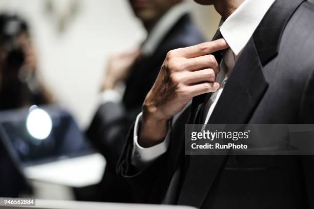 close up of businessman adjusting necktie - eleganza foto e immagini stock