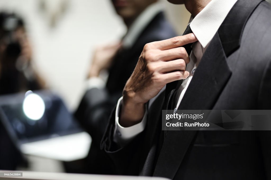 Close up of businessman adjusting necktie