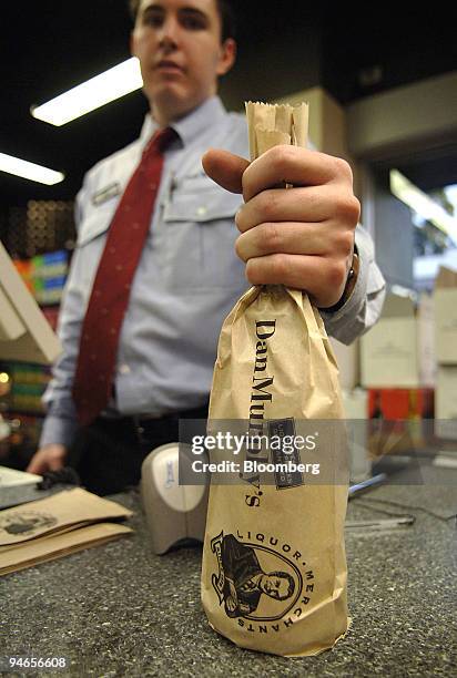 An employee prepares to scan a bottle of wine in a Dan Murphy's Liquor Outlet store in Sydney, Australia, Tuesday July 18, 2006. Woolworths Ltd.,...