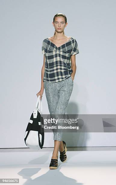 Model walks down the catwalk wearing a navy/ecru rayon plain top over a tweed silk cotton trouser and carrying a navy/white oversized bag during the...