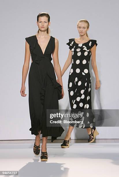 Model wearing a black fluid asymetric ruffle dress, left, and another wearing a super dot print ruffle dress walk down the catwalk during the showing...