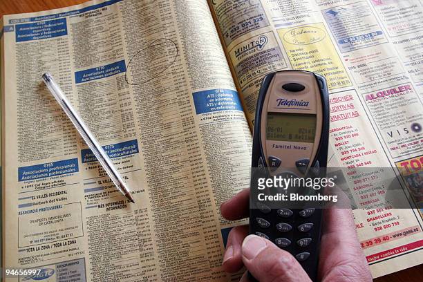 User poses with a mobile phone and a directory published by Telefonica Publicidad e Informacion SA in Madrid, Spain, Friday, April 28, 2006. Yell...