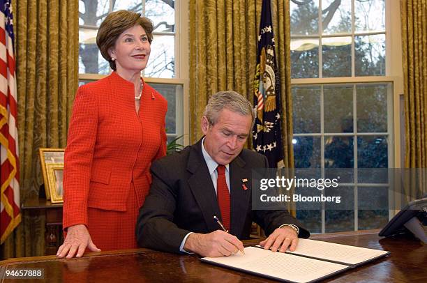 First Lady Laura Bush looks on as President George W. Bush signs the Presidential Proclamation in honor of American Heart Month from the Oval Office...
