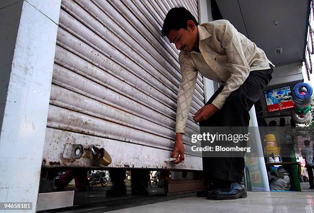 Shop owner pulls up the shutter of his shop situated outside Mumbai, India, on Thursday, Nov. 29, 2007. India's economy grew last quarter at the...