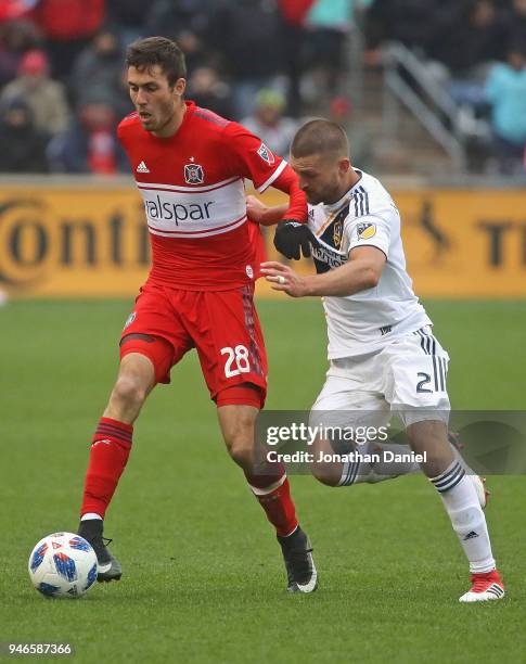 Elliot Collier of the Chicago Fire is pressured by Perry Kitchen of Los Angeles Galaxy at Toyota Park on April 14, 2018 in Bridgeview, Illinois. The...