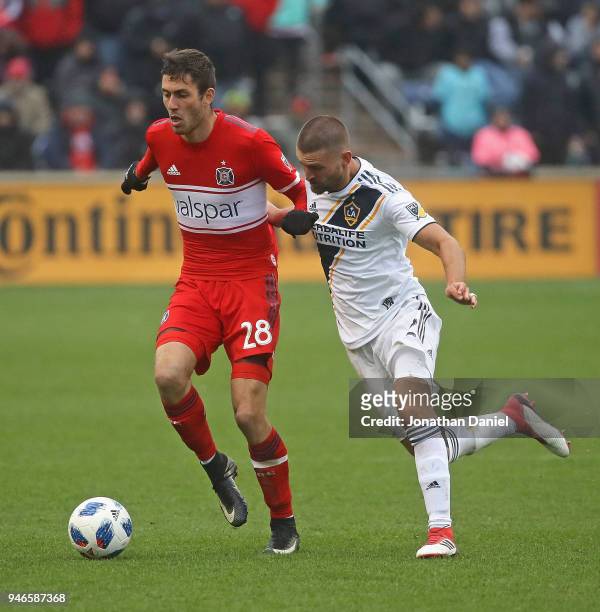 Elliot Collier of the Chicago Fire is pressured by Perry Kitchen of Los Angeles Galaxy at Toyota Park on April 14, 2018 in Bridgeview, Illinois. The...