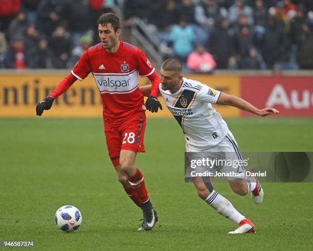 Elliot Collier of the Chicago Fire is pressured by Perry Kitchen of Los Angeles Galaxy at Toyota Park on April 14, 2018 in Bridgeview, Illinois. The...