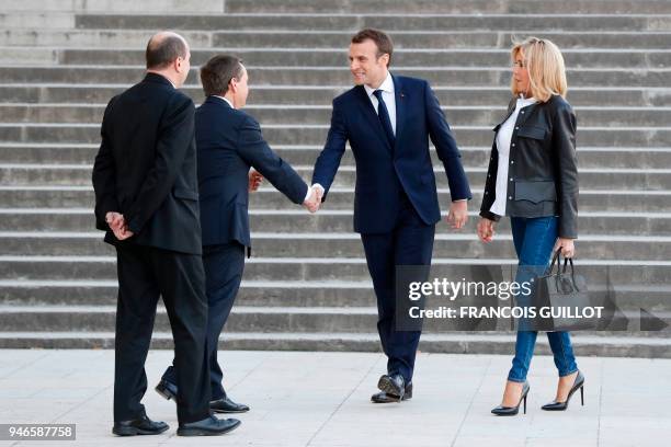 French President Emmanuel Macron , flanked by his wife Brigitte Macron , arrives to attend an interview with journalists from BFM television and the...