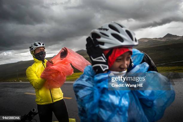 Wang Chao and Wang Runxi puts on a poncho during a sudden rain and hail storm on Mount Haizi, elevation 15, 000 feet, in Litang county, Garze,...