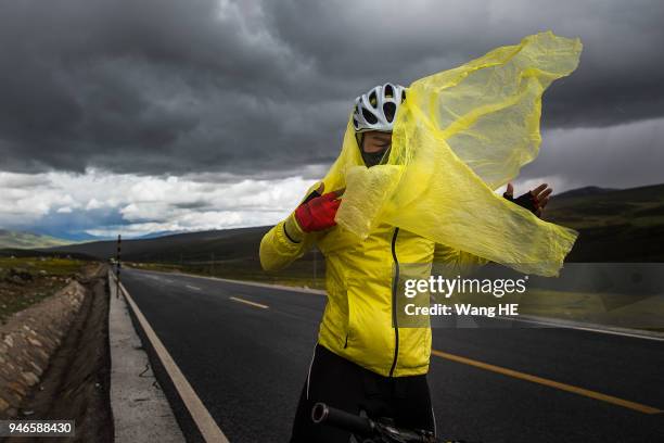 Wang Chao puts on a poncho during a sudden rain and hail storm on Mount Haizi, elevation 15, 000 feet, in Litang county, Garze, Sichuan, China. July...