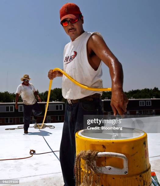 Worker who identified himself only as "Rafael" fills a insulated drinking container while working on an apartment building roof Tuesday, July 18 in...