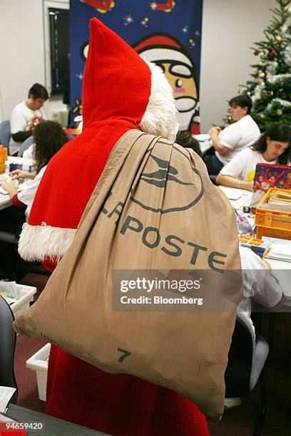Postal worker dressed as Santa carries letters addressed to Santa Claus at the La Poste office in Libourne, in the Bordeaux region of France, on...
