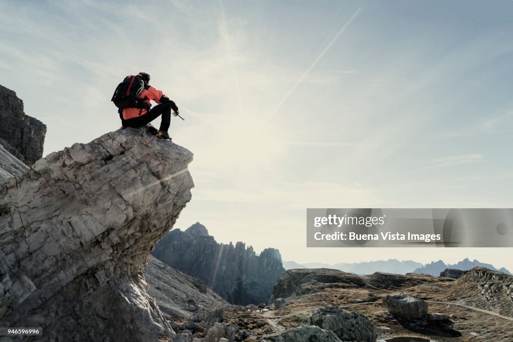 Climber sitting on a rock and watching a mountain range.