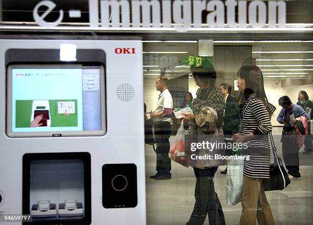 Travellers wait behind a fingerprint reading device at the immigration area of Narita International Airport in Chiba prefecture, Japan, on Tuesday,...