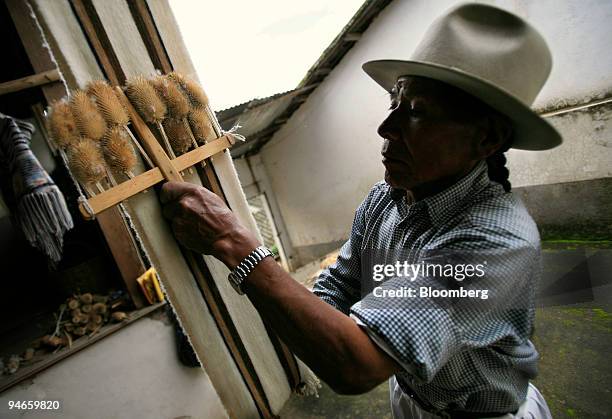 Jose Carlos de la Torre uses a brush made up of teasel to smooth an alpaca wool scarf inside his workshop in Carabuela, Ecuador, Wednesday, November...