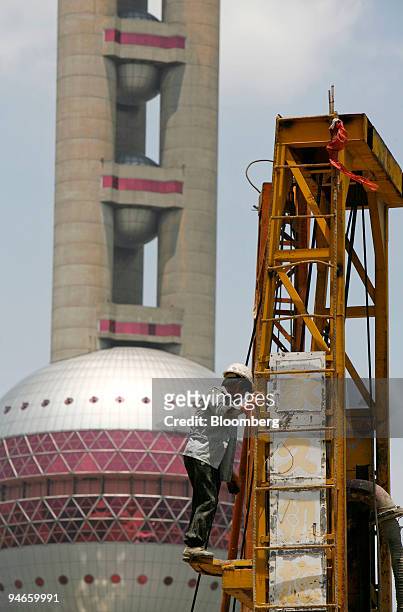 Worker climbs onto a drilling platform in front of the Oriental Pearl TV Tower at the construction site where Sun Hong Kai Properties Capital Market...