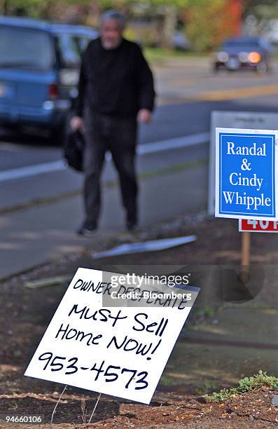 Hand-lettered sign indicating "Owner Desperate Must Sell Home Now!" is posted near commercially-printed home for sale signs in Eugene, Oregon,...