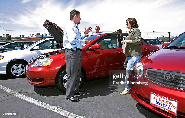Shawn Hayes, a salesman with Toyota of El Cajon, left, shows prospective buyers Jack and Kathy Stanton a Toyota Corolla as the couple shops for a new...