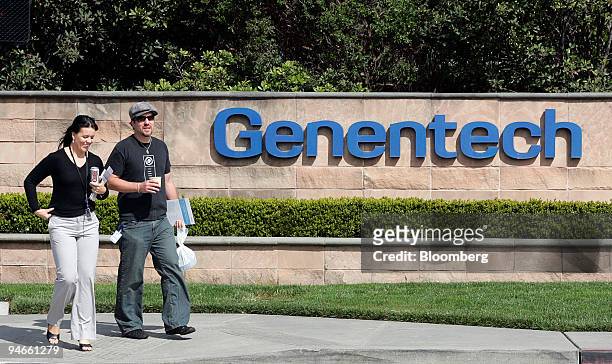 People walk past a Genentech Inc. Sign in San Francisco, California, on Wednesday, March 29, 2007. Biotechnology companies including Genentech Inc....
