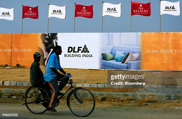 Workers cycle past the site of a proposed apartment by DLF Universal Ltd. In DLF City, Gurgaon, India, on Sunday, September 17, 2006.