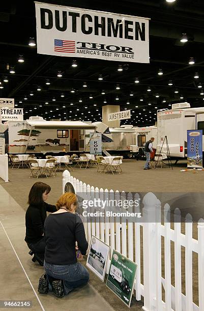 Katie Amick, left, and Heidi McHugh, right, of Thor Industries, post advertising signs at the company's display booth before tomorrow's 45th annual...