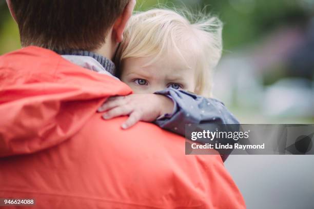 blauwe ogen van een klein blond meisje kijkt over papa's schouder - compassionate eye stockfoto's en -beelden