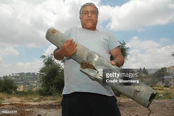 Man holds the remnants of a rocket that landed in an open area near Safed, in Upper Galilee, Israel, Friday, July 14, 2006. Israel pounded Hezbollah...