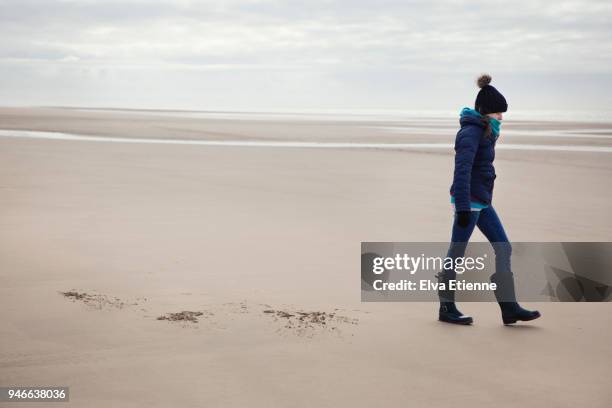 teenage girl in winter clothing walking along a deserted sandy beach - 15 years girl bare stock pictures, royalty-free photos & images