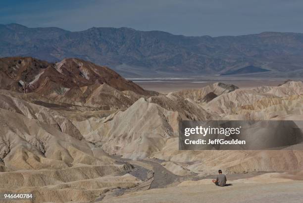 jonge man zitten in de buurt van een formatie van de badlands boven badwater basin - jeff goulden stockfoto's en -beelden