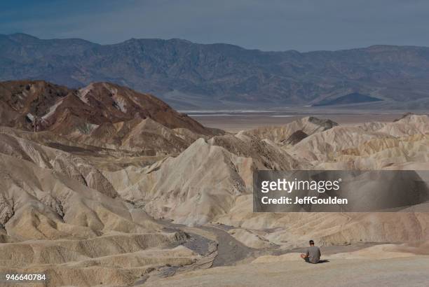 young man sitting near a badlands formation above badwater basin - jeff goulden stock pictures, royalty-free photos & images