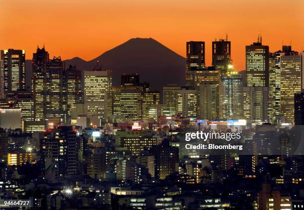 Mount Fuji, Japan's highest peak, emerges through the Shinjuku skyscraper district at dusk, in Tokyo, Japan, on Thursday, Nov. 22, 2007. Japan's...