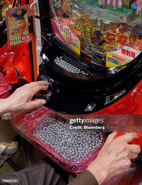 Man amasses a pile of small, steel balls while playing pachinko, a Japanese version of pinball, at a pachinko parlor in central Tokyo, Friday, June...