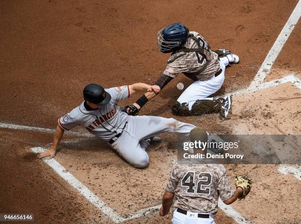 Nick Hundley of the San Francisco Giants, scores ahead of the tag of Austin Hedges of the San Diego Padres, as Joey Lucchesi looks on during the...