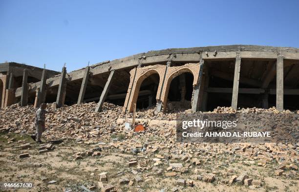 An Iraqi fighter from the Hashed al-Shaabi checks the severely damaged tomb of the late Iraqi dictator Saddam Hussein in the village of Al-Awja, on...