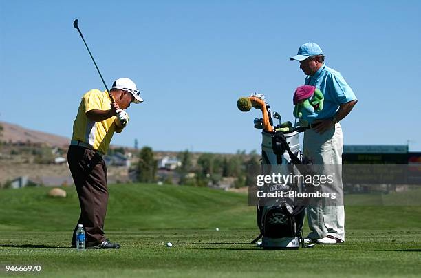 Tadd Fujikawa, a 16-year-old golfer from Hawaii, left, warms up on the driving range with coach Mike Shannon of Sea Island Golf Club in Georgia...