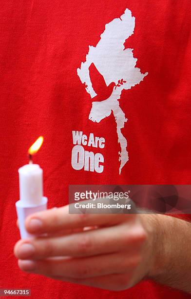 Student with an emblem showing a dove atop Myanmar holds a candle during a protest against the military rulers of Myanmar, near the venue of the 13th...