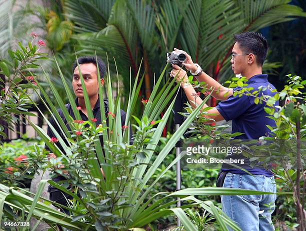 Police watch and film three University of Singapore overseas students protesting Myanmar's military junta, venue of the 13th Summit of the...