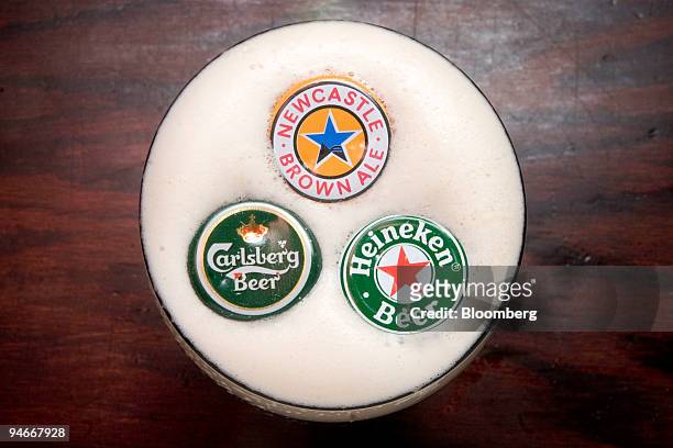 Carlsberg, Heineken, and Newcastle bottle caps are arranged for an illustration at Paddy McGuire's Pub in New York, New York, U.S., on Thursday, Nov....