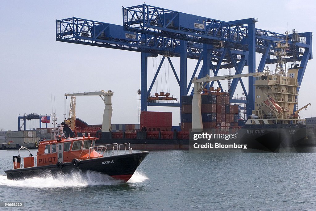 A small boat passes in front of a ship unloading goods at th