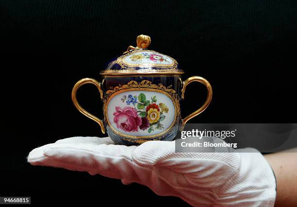 Porcelain chocolate pot given to Queen Elizabeth II by Pope Pius XII to celebrate her 1947 wedding to Prince Phillip is displayed by a member of...