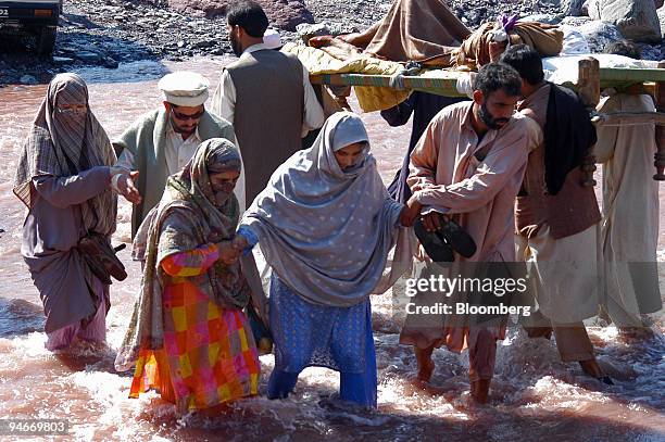 Earthquake survivors cross a flooded stream Sunday, October 9, 2005 in the town of Balakot in the north of Pakistan. The major quake on Saturday...