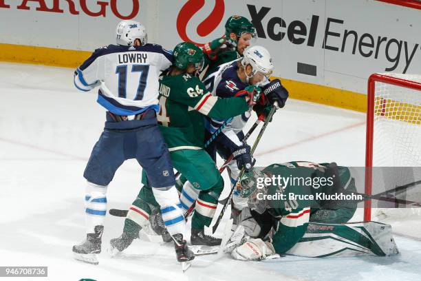 Devan Dubnyk covers the puck while his teammates Mikael Granlund and Nick Seeler of the Minnesota Wild battle with Joel Armia and Adam Lowry of the...