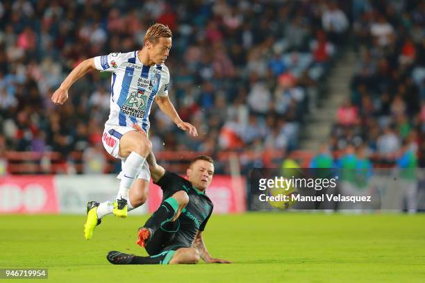 Keisuke Honda of Pachuca jumps with the ball over the slide of Jonathan Rodriguez of Santos during the 15th round match between Pachuca and Santos...