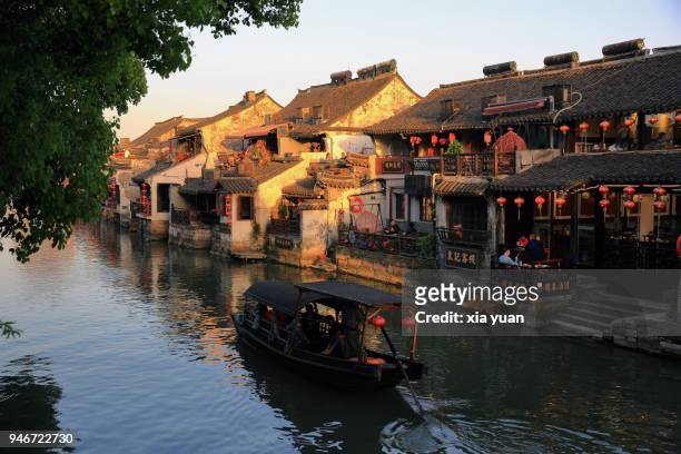 rowboat rowing on canal in xitang ancient town at sunset,china - jiaxing fotografías e imágenes de stock