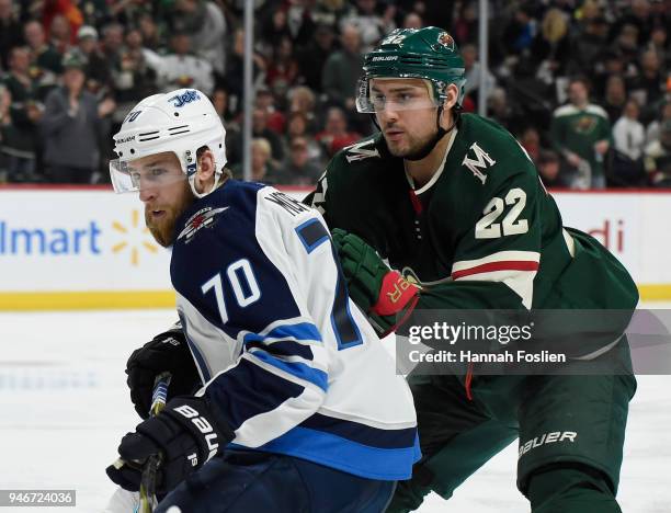 Joe Morrow of the Winnipeg Jets and Nino Niederreiter of the Minnesota Wild skate after the puck during the second period in Game Three of the...